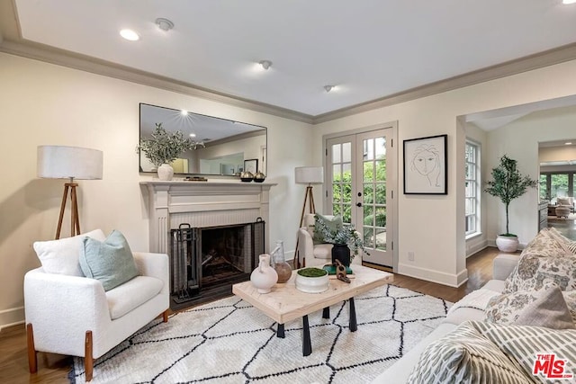 living room featuring french doors, ornamental molding, a brick fireplace, and light wood-type flooring