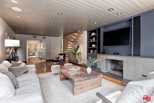 living room featuring a brick fireplace, built in shelves, wooden ceiling, and hardwood / wood-style flooring