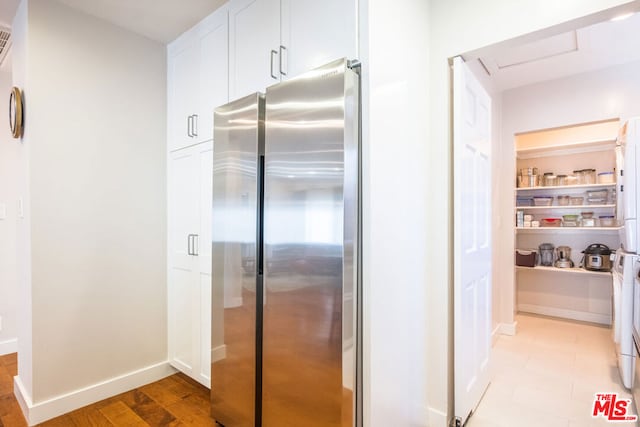 kitchen with white cabinetry and stainless steel fridge