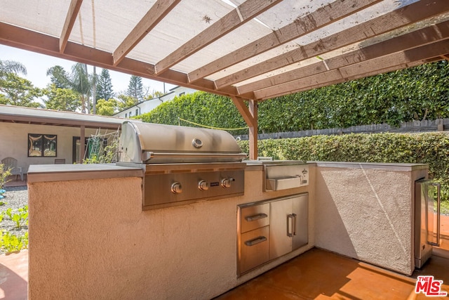 view of patio with area for grilling, a pergola, and exterior kitchen