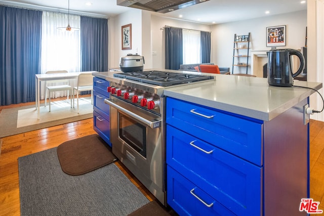 kitchen featuring pendant lighting, stainless steel stove, blue cabinets, a center island, and plenty of natural light