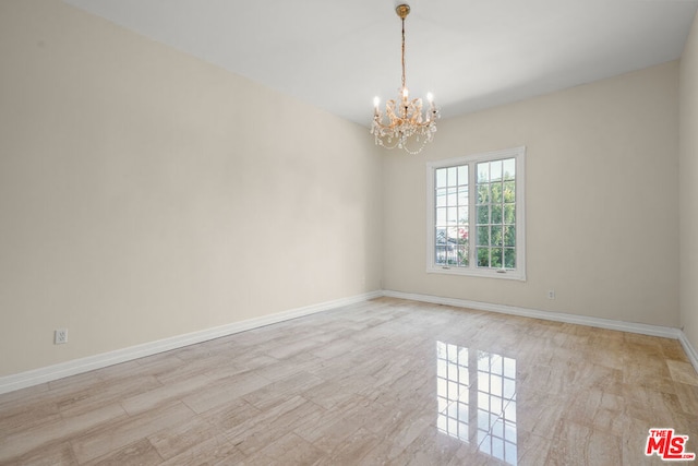 unfurnished room featuring a chandelier