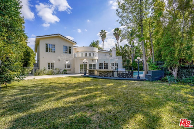 rear view of property with a yard and a balcony