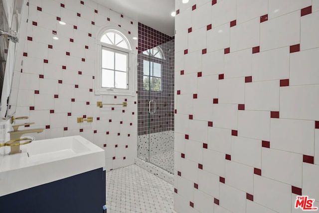 bathroom with tile patterned flooring, vanity, tile walls, and walk in shower