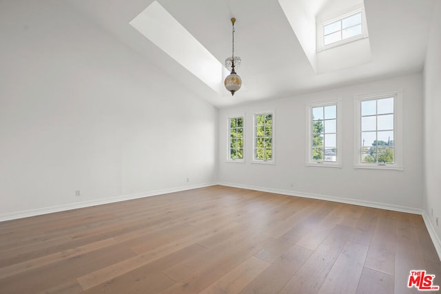 unfurnished room featuring wood-type flooring and lofted ceiling with skylight