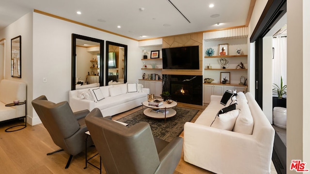 living room with crown molding, a high end fireplace, and light hardwood / wood-style floors