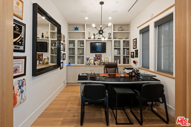 interior space featuring pendant lighting, built in features, light hardwood / wood-style floors, and white cabinets