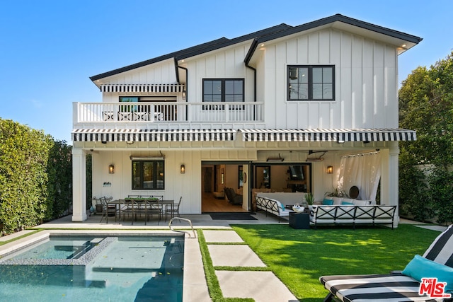 back of house with an outdoor living space, a lawn, a patio, and a balcony