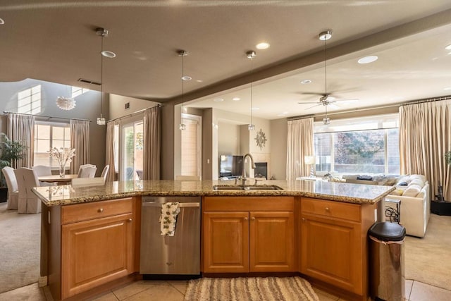 kitchen with sink, light stone counters, hanging light fixtures, dishwasher, and an island with sink