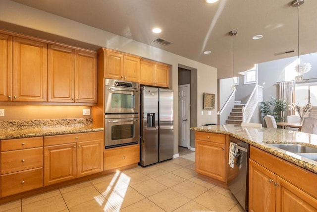 kitchen with light tile patterned flooring, stainless steel appliances, light stone countertops, and hanging light fixtures