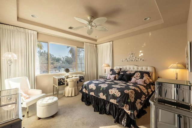 carpeted bedroom with ceiling fan and a tray ceiling