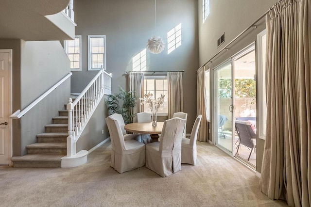 dining space featuring light colored carpet and a towering ceiling