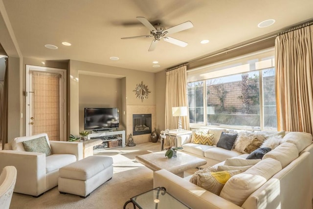 living room featuring a tile fireplace, light colored carpet, and ceiling fan