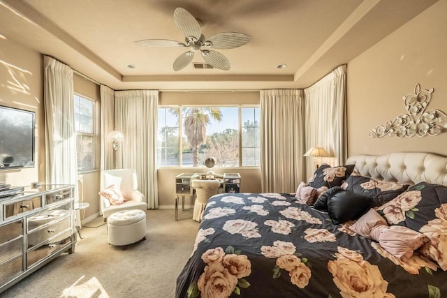 carpeted bedroom featuring ceiling fan and a raised ceiling