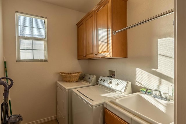 clothes washing area with independent washer and dryer, cabinets, and sink