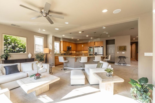 living room with sink, light carpet, and ceiling fan