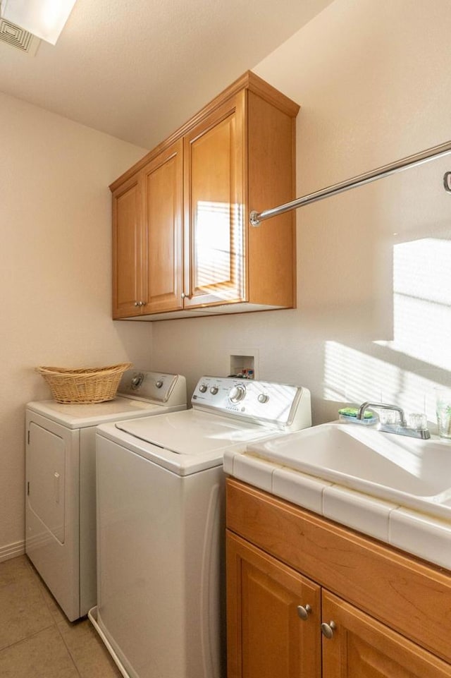 laundry room with cabinets, washer and dryer, and light tile patterned floors