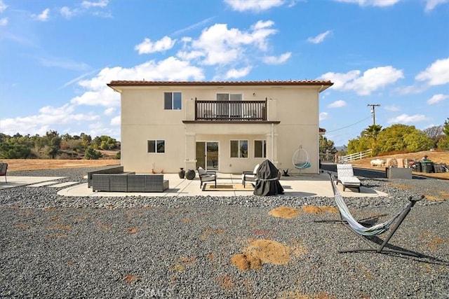 rear view of house with an outdoor living space, a patio, and a balcony