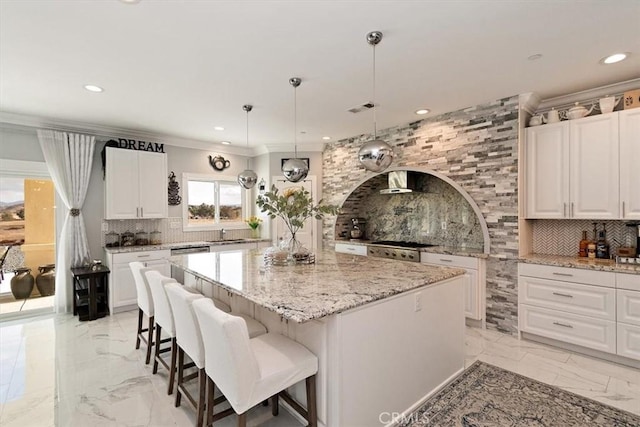 kitchen featuring white cabinetry, light stone counters, tasteful backsplash, a kitchen island, and decorative light fixtures