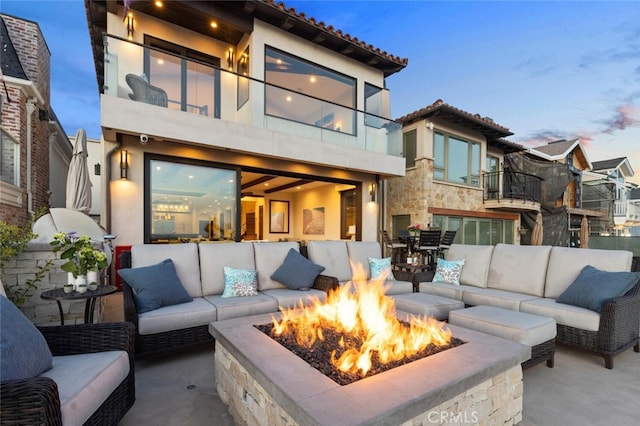 patio terrace at dusk with an outdoor living space with a fire pit