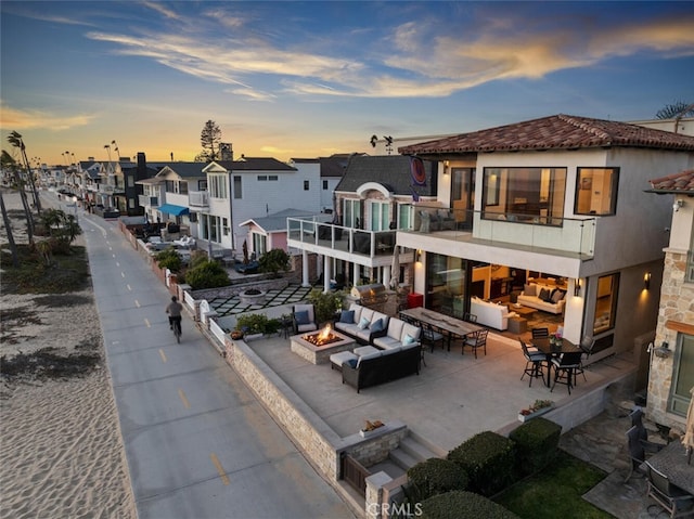 back house at dusk featuring an outdoor living space with a fire pit and a patio area