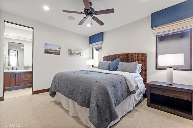 carpeted bedroom with ensuite bathroom, sink, and ceiling fan