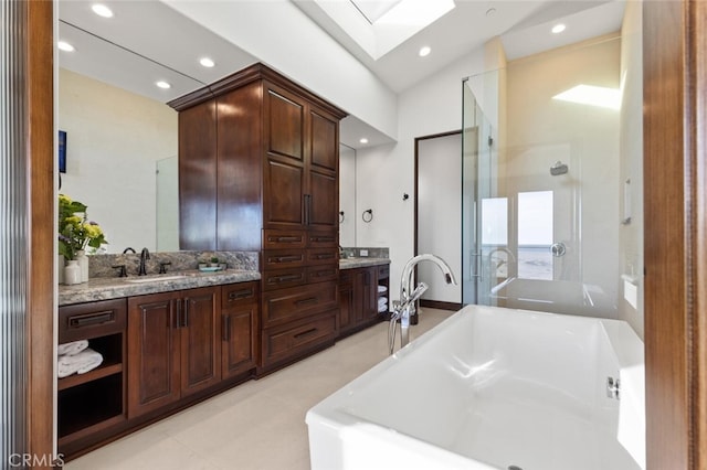 bathroom featuring vanity, a bathtub, and vaulted ceiling with skylight