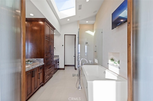 bathroom with vanity, lofted ceiling with skylight, and a bathing tub