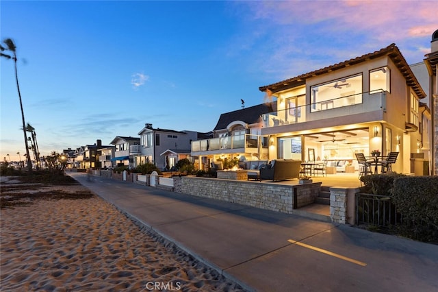 view of front of property with ceiling fan, a balcony, an outdoor hangout area, and a patio