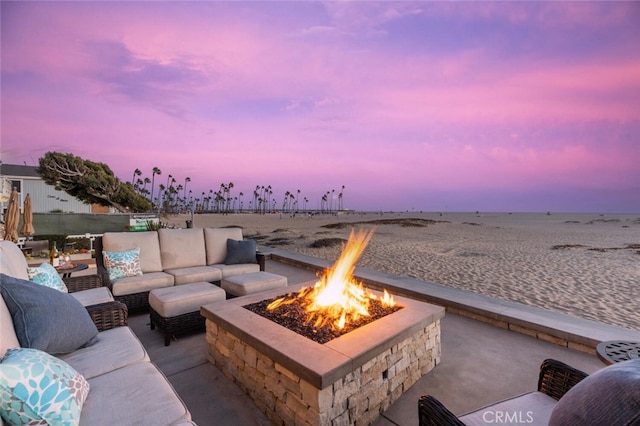 patio terrace at dusk with an outdoor living space with a fire pit and a water view