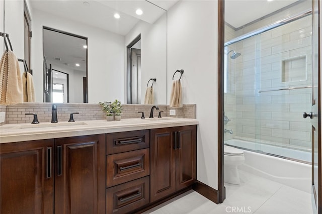 full bathroom featuring bath / shower combo with glass door, vanity, backsplash, and toilet