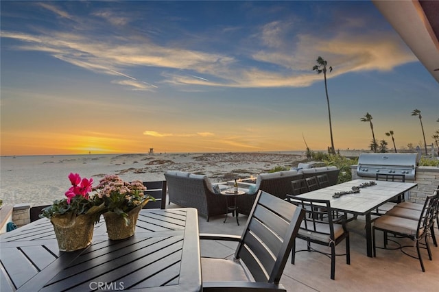 patio terrace at dusk featuring a water view, area for grilling, a beach view, and grilling area