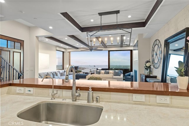 kitchen featuring pendant lighting, light stone countertops, and sink