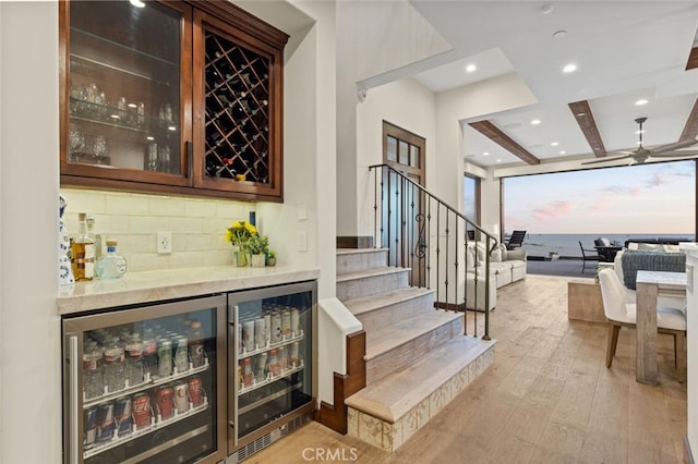 bar with wine cooler, ceiling fan, light hardwood / wood-style flooring, and backsplash