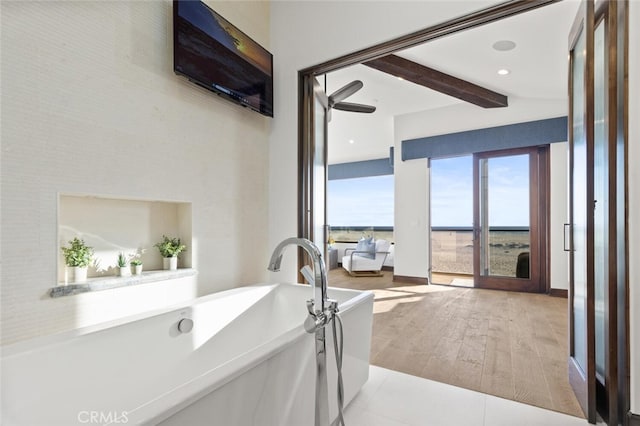 bathroom featuring wood-type flooring, beam ceiling, and a bathtub