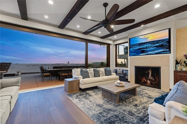 living room featuring beamed ceiling, dark hardwood / wood-style floors, and ceiling fan