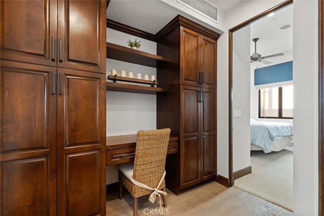 office space featuring built in desk, light hardwood / wood-style floors, and ceiling fan