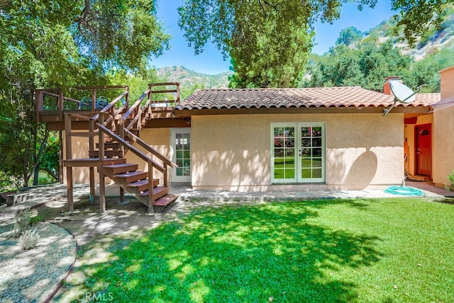 back of property featuring a yard and a deck with mountain view