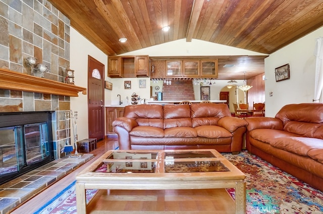 living room with wood ceiling, lofted ceiling with beams, a tile fireplace, and light hardwood / wood-style flooring