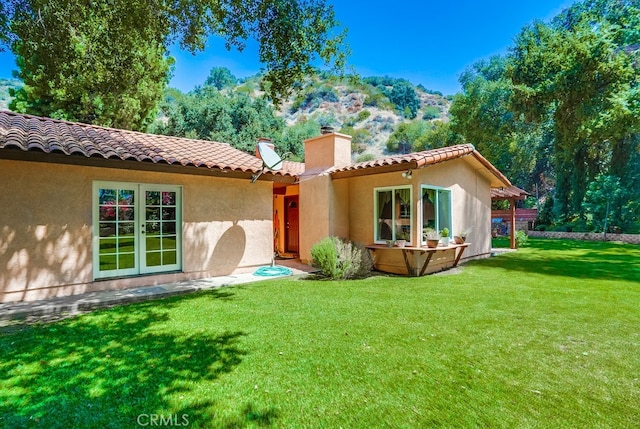 back of property featuring french doors and a lawn