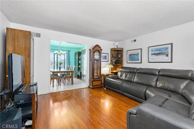 living room with hardwood / wood-style floors, a textured ceiling, and an inviting chandelier