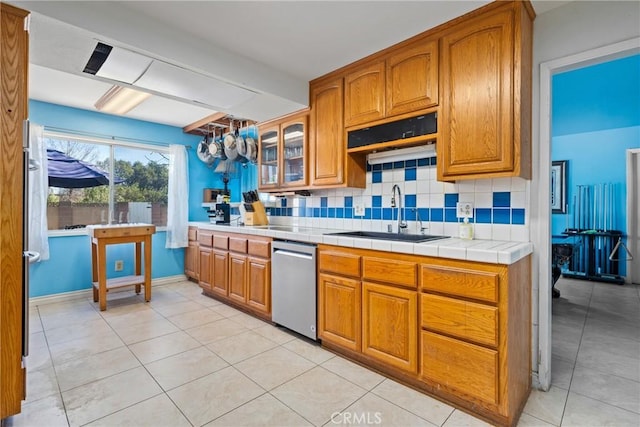 kitchen featuring tile countertops, tasteful backsplash, dishwasher, sink, and light tile patterned floors