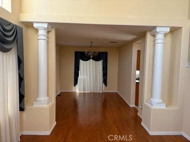 unfurnished dining area with wood-type flooring and ornate columns