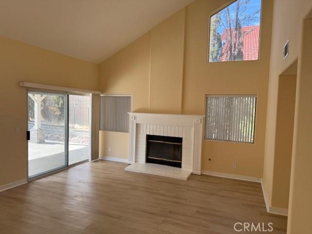 unfurnished living room with hardwood / wood-style flooring, a fireplace, and high vaulted ceiling