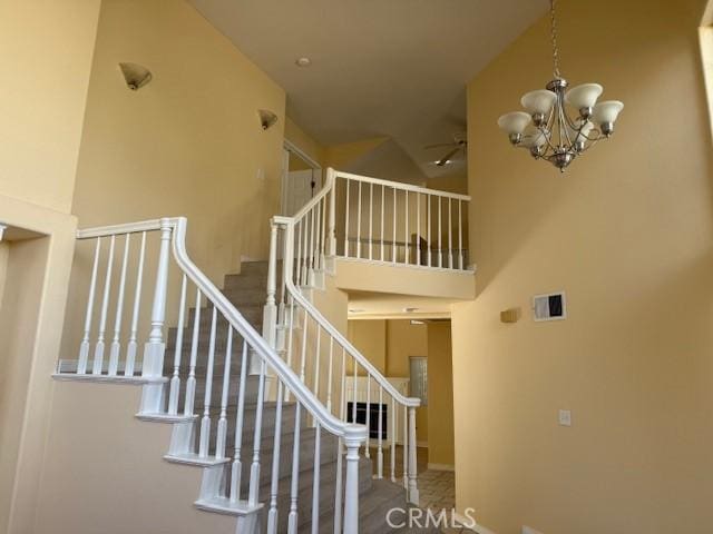 stairs featuring a towering ceiling and a chandelier