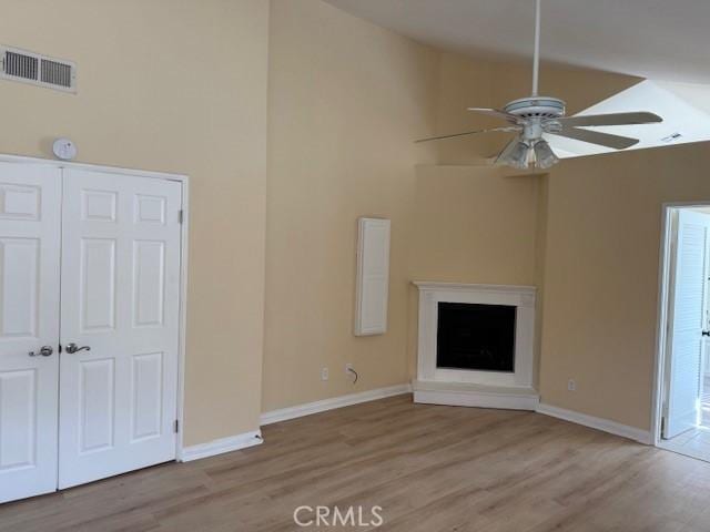 unfurnished living room featuring high vaulted ceiling, light hardwood / wood-style floors, and ceiling fan