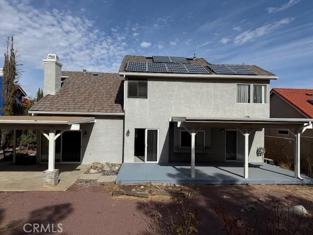 back of house with a patio and solar panels