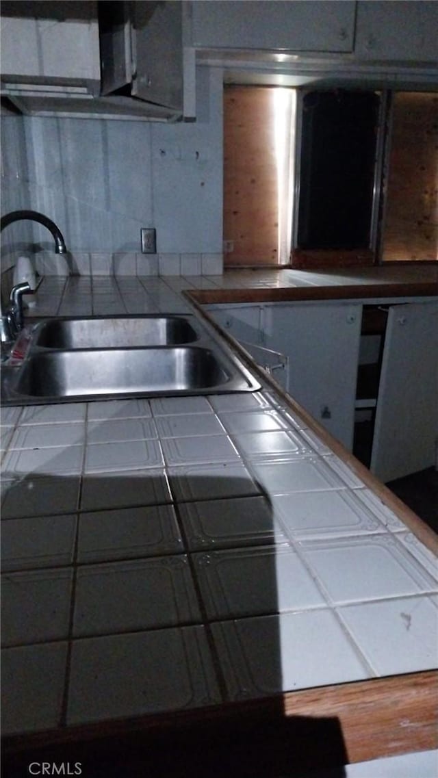 kitchen featuring tasteful backsplash, sink, and tile countertops