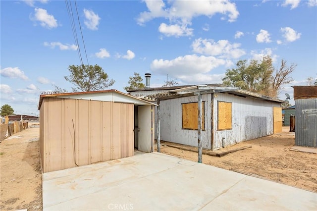 rear view of house featuring an outdoor structure and a patio area