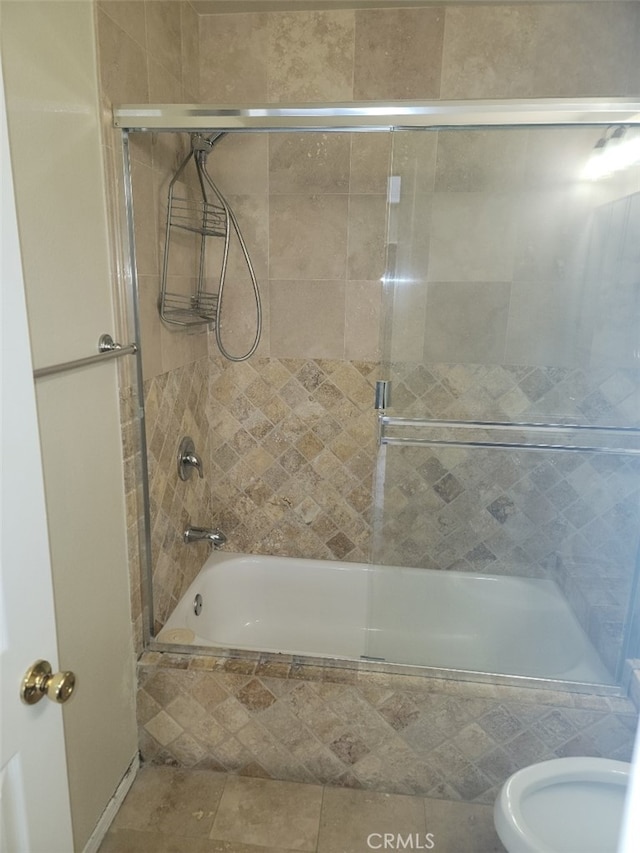 bathroom with bath / shower combo with glass door and toilet